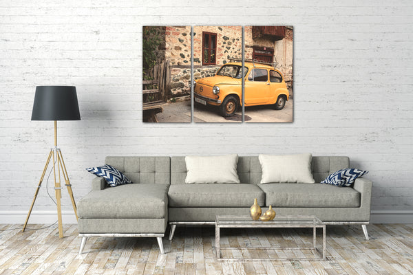 Leinwandbild Autobilder Oldtimer gelb vor Dorf-Kulisse