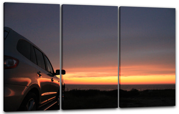 Leinwandbild Stehenes Auto vor Sonnenuntergang am Horizont