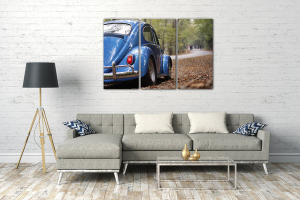 Leinwandbild Blaues Auto Käfer auf Waldstrße von hinten rechts