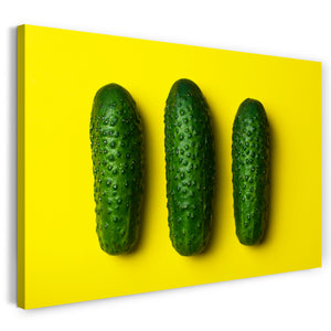 Leinwandbild Essensbilder Gemüse drei Gurken vor gelbem Hintergrund