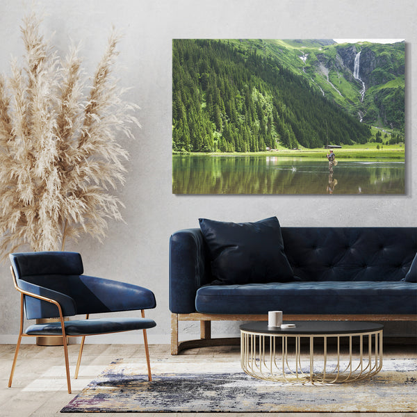 Leinwandbild Landschaftsbilder Fischer kniehoch im Wasser vor grüner Bergkulisse