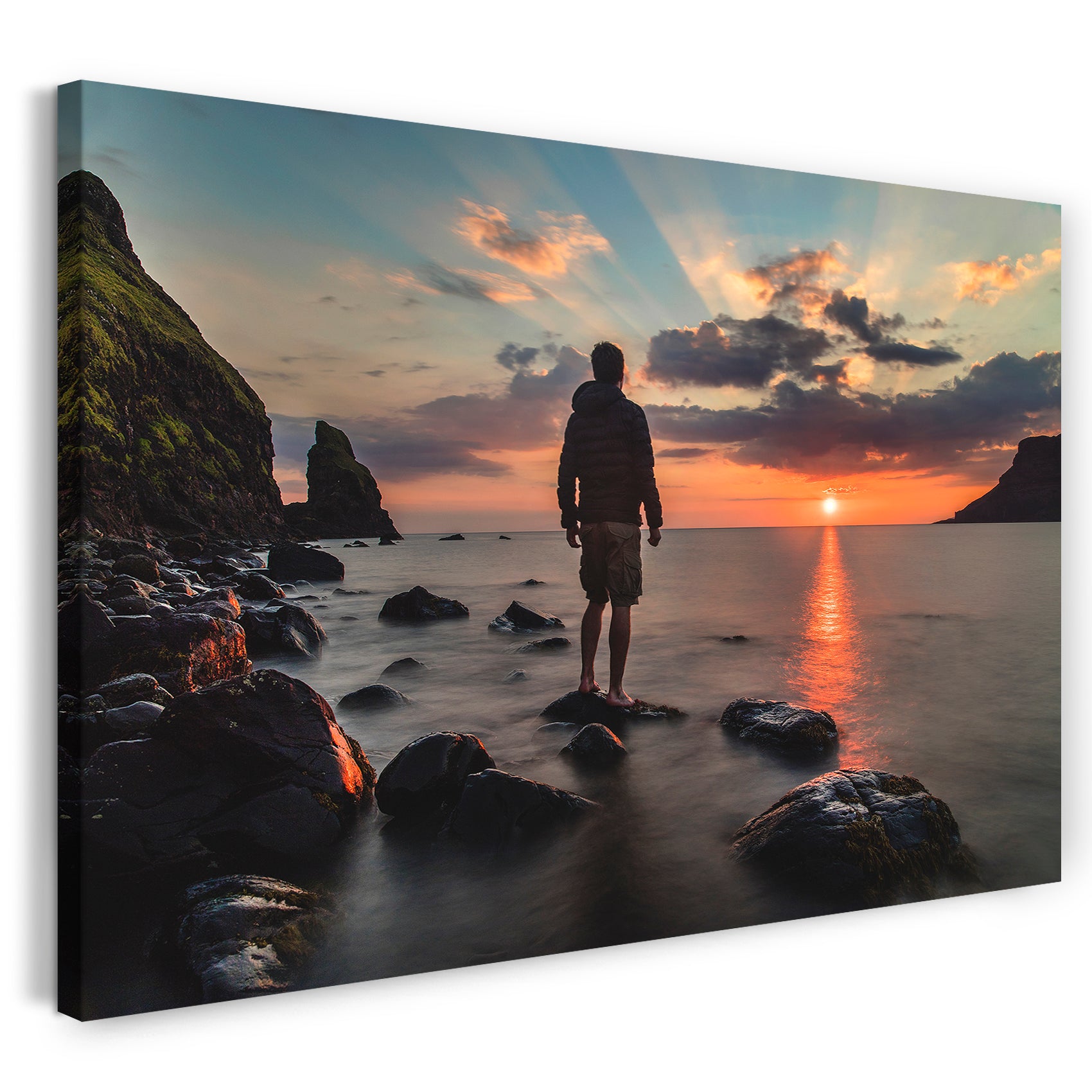 Leinwandbild Einsamer Mann auf Felsstein vor Meeres-Kulisse mit Sonnenuntergang