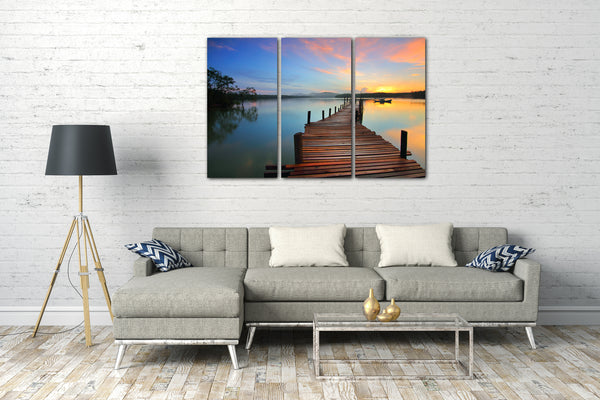 Leinwandbild Holzsteg am See, hinten Boot und Sonnenuntergang, schöne Farbtöne