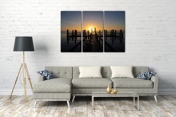 Leinwandbild Holzsteg im Meer unter aufgehender Sonne