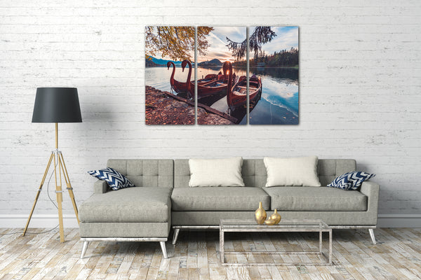 Leinwandbild Drei Holzboote mit Schwankopf auf blauem See, davor Herbstlaub