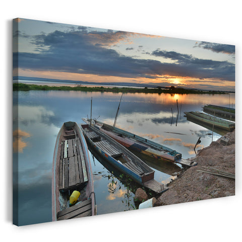Leinwandbild Vier alte Holzboote auf spiegelndem Wasser vor Sonnenuntergang
