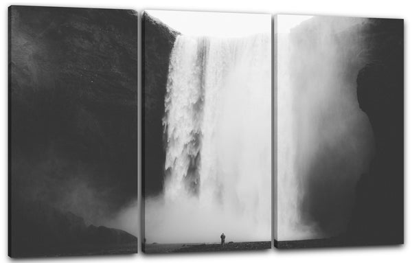 Leinwandbild Naturbilder Riesiger Wasserfall, unten steht eine Person, schwarz-weiß